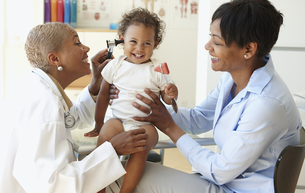 Mother holding baby while doctor checks her ears